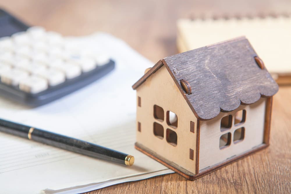 A budget notebook, calculator, and model home, photographed by Sasun Bughdaryan